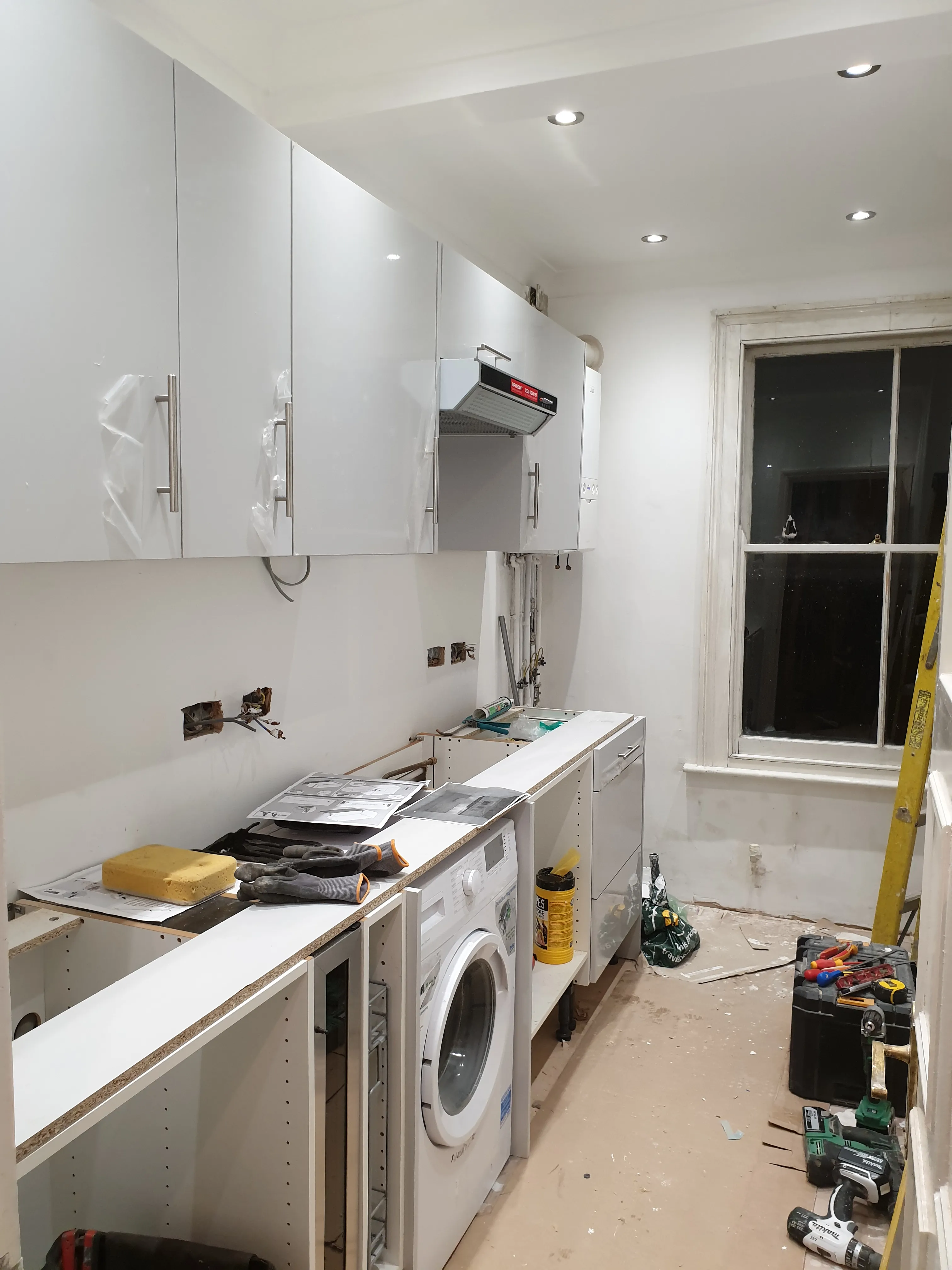 Kitchen mid-progress - white cabinetry installation with modern hood