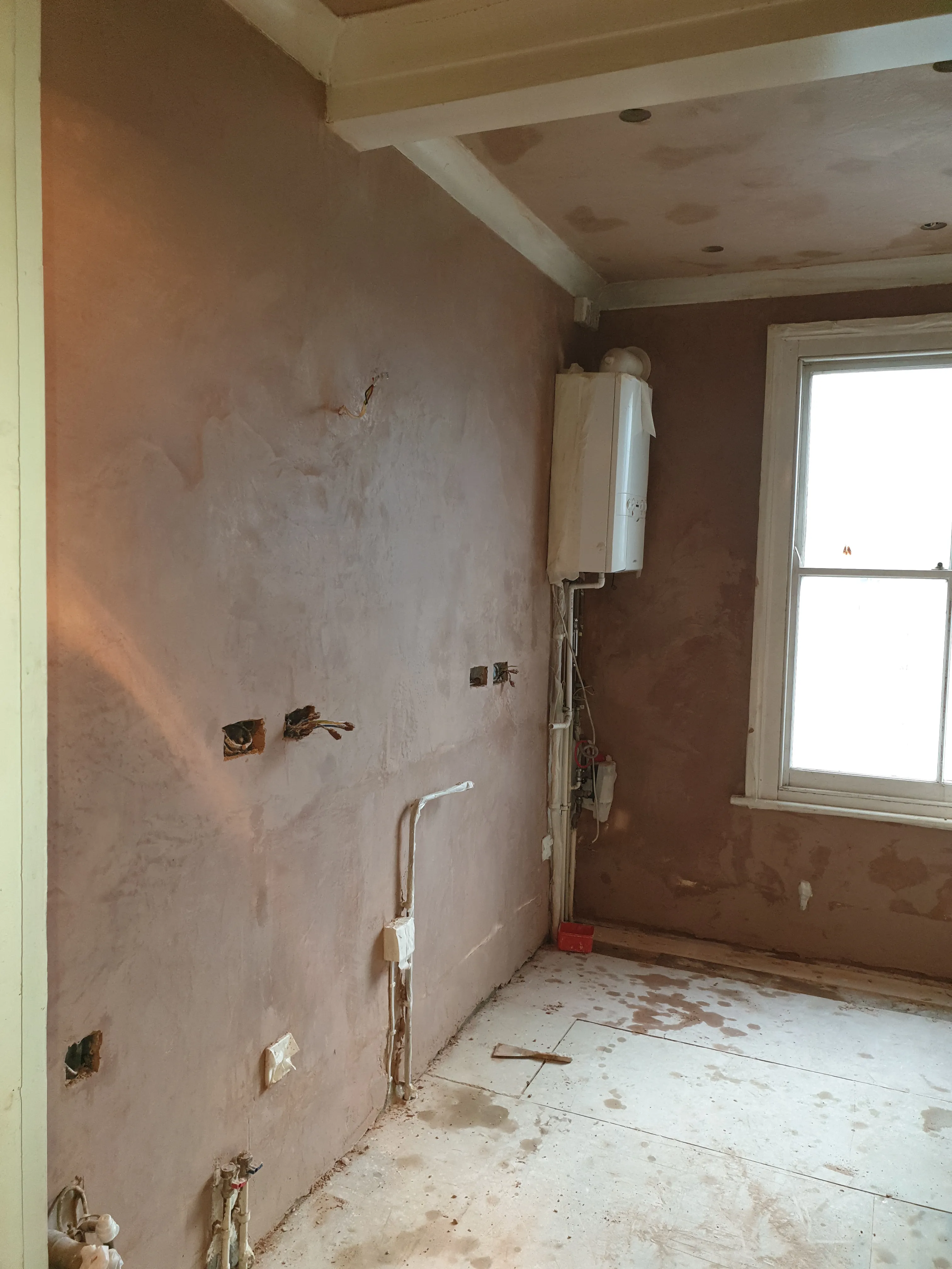Kitchen during renovation - gutted space with exposed plumbing